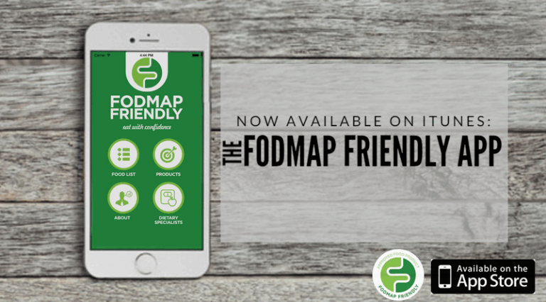 A smartphone displaying the FODMAP Friendly app sits on a wooden surface. Text reads, Now available on iTunes: The FODMAP Friendly App. App Store and FODMAP Friendly logos are also shown.