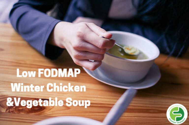 A person holds a spoon over a bowl of soup on a wooden table. Text reads: Low FODMAP Winter Chicken & Vegetable Soup. A green FODMAP Friendly logo appears in the bottom right corner.