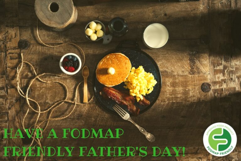 A rustic table with pancakes, scrambled eggs, bacon, berries, and milk. Green text reads, HAVE A FODMAP FRIENDLY FATHERS DAY! with a FODMAP Friendly logo in the corner.