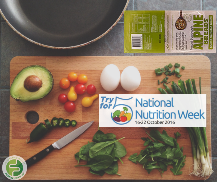 A wooden chopping board with spinach, spring onions, a halved avocado, cherry tomatoes, jalapeño slices, two eggs, and a knife. Nearby are a frying pan, Alpine Breads packet, and a National Nutrition Week 2016 logo.
