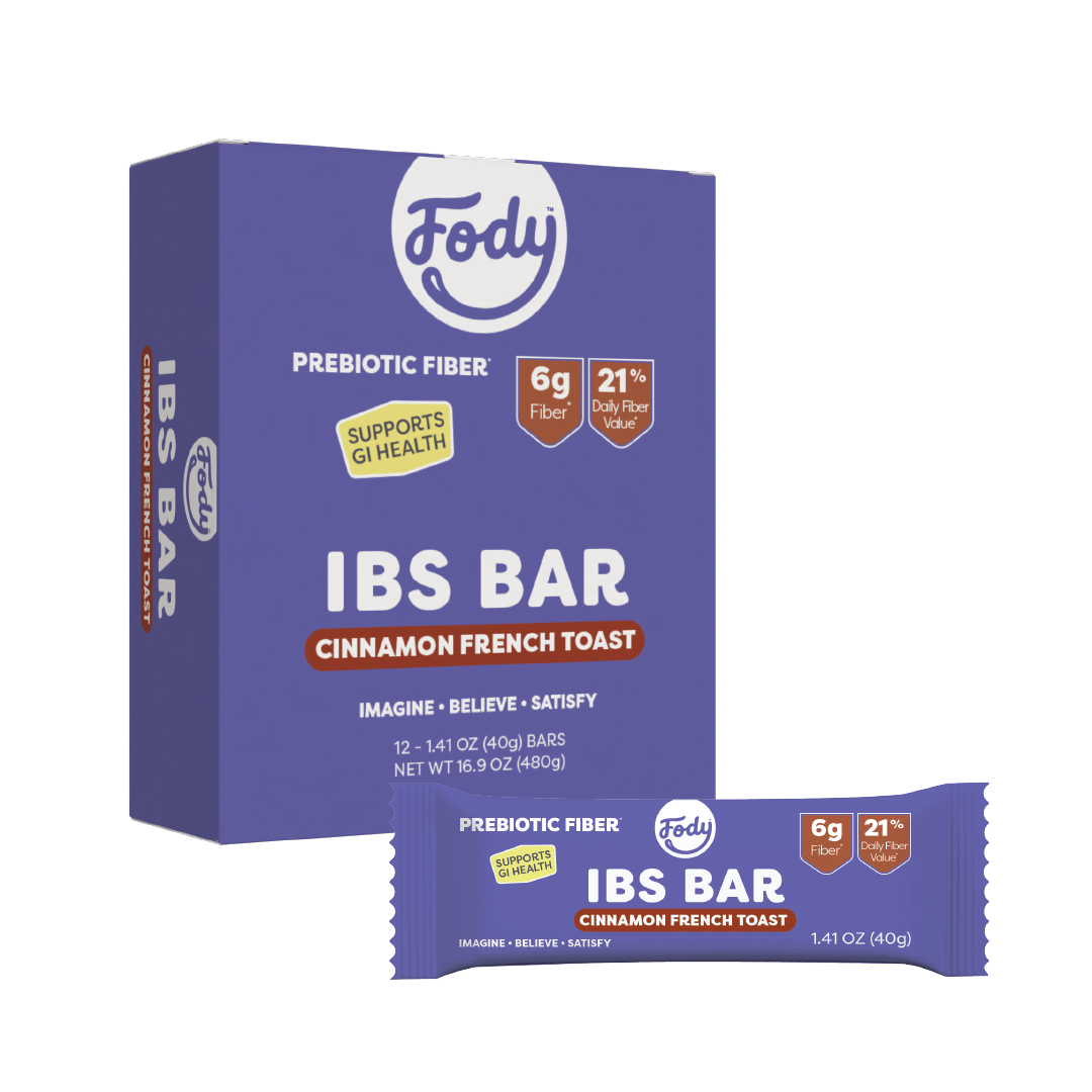 A purple Fody IBS Bar box with High Fibre Cinnamon French Toast flavour text stands behind a single wrapped snack bar. The packaging highlights prebiotic fibre, 6g fibre, 21% daily value, and a supports GI health badge.