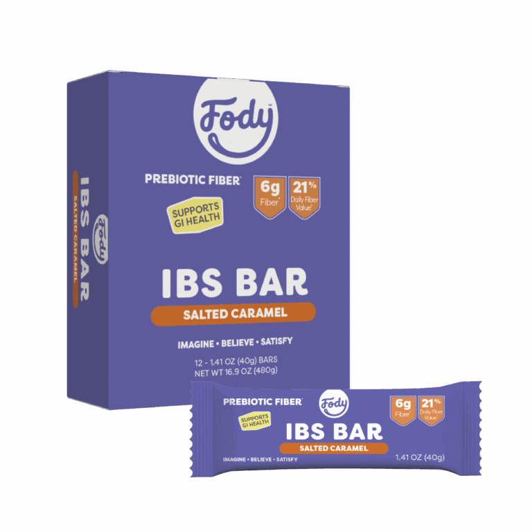 A box and a single wrapped Fody Salted Caramel Snack Bar. The purple packaging with orange and white text highlights its high fibre content, featuring “prebiotic fibre,” “6g fibre,” and “21% daily fibre value.”.