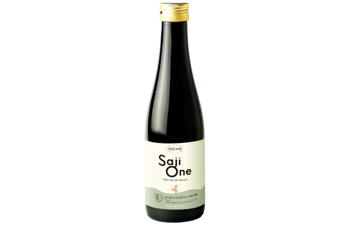 A dark glass bottle with a gold cap labelled Saji One in large text, featuring Organic Sea Buckthorn and other details in Japanese, plus a small emblem on a light-coloured label. The bottle stands upright against a white background.